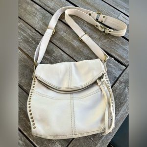 The Sak crossbody bag with brass hardware, small decorative rivets along front